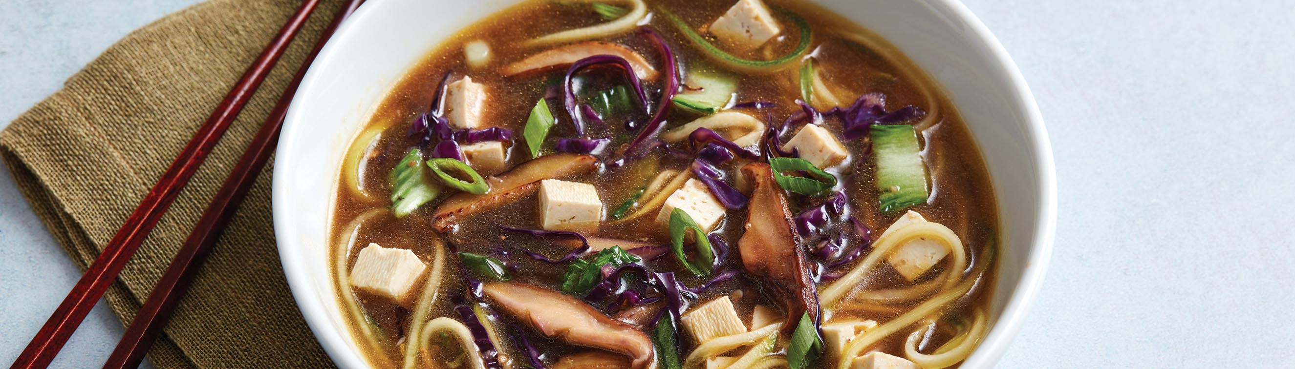 A bowl of Zucchini and yellow squash noodles topped with tofu, bok choy, cabbage, and mushrooms in a hot miso broth.
