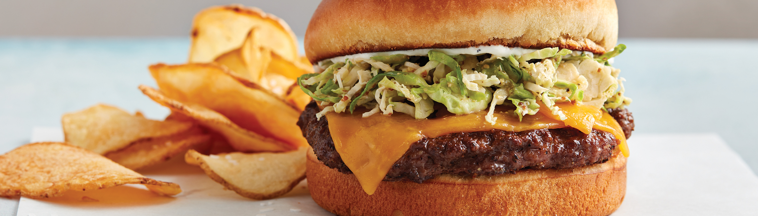 A quarter-pound burger with Cheddar cheese, maple Brussels sprout slaw and horseradish aioli served with house chips.