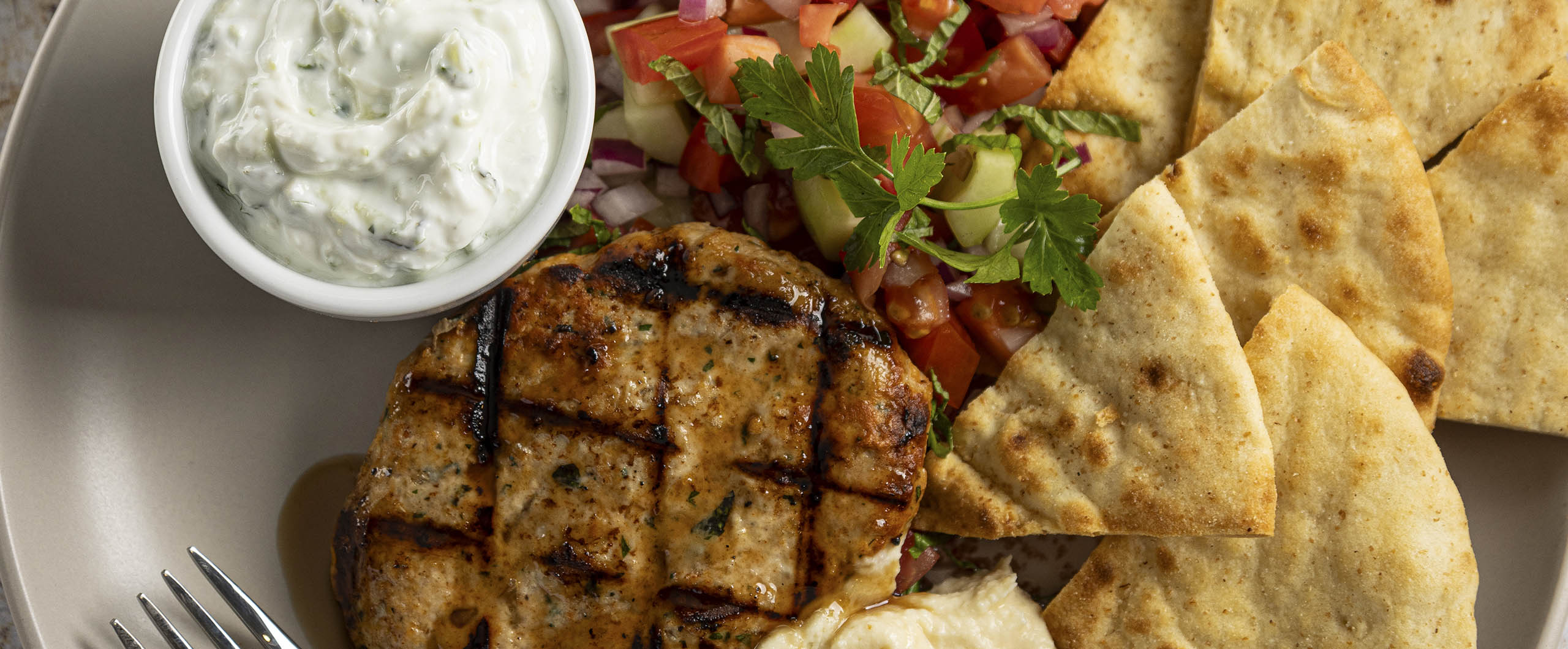 Turkey patty with pomegranate molasses, served with hummus and tzatziki. Served with pita chips and cucumber tomato salad.